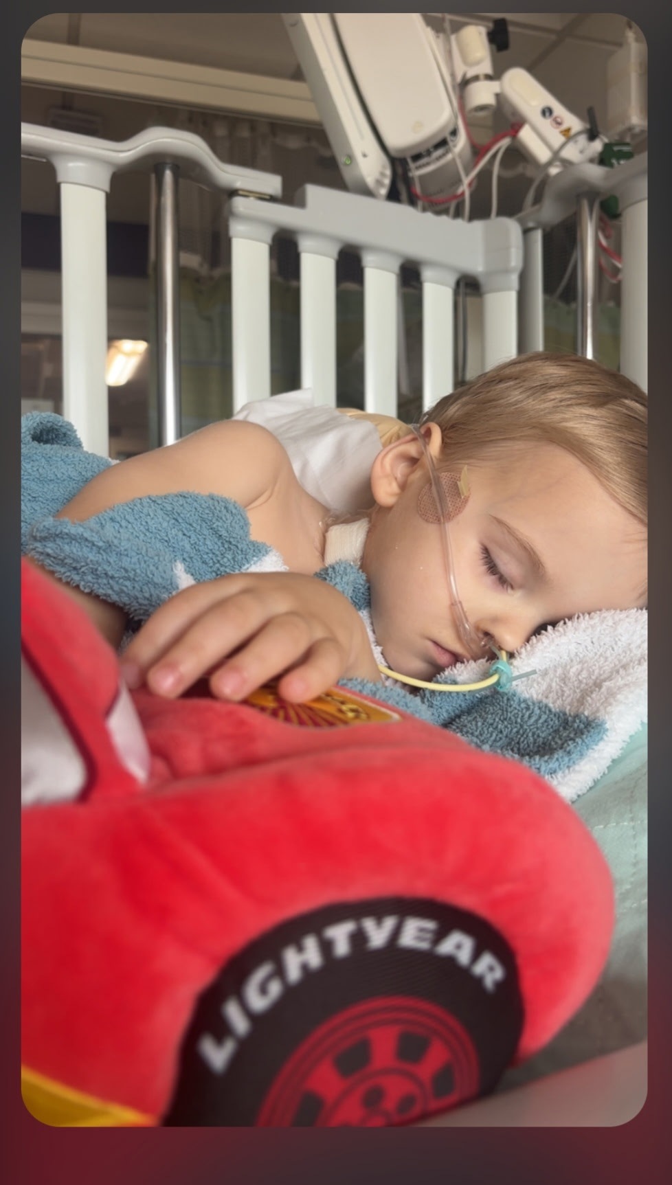 Tucker resting in a hospital bed with his toy car